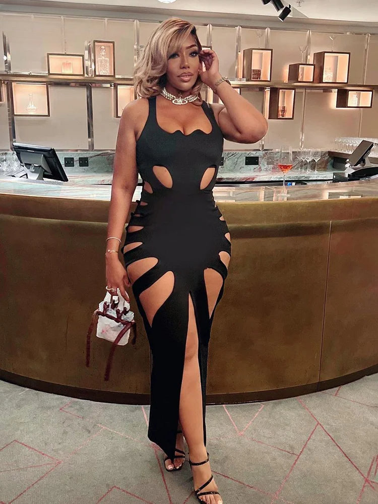 Woman in a black dress with cut-out design standing in a modern interior setting.