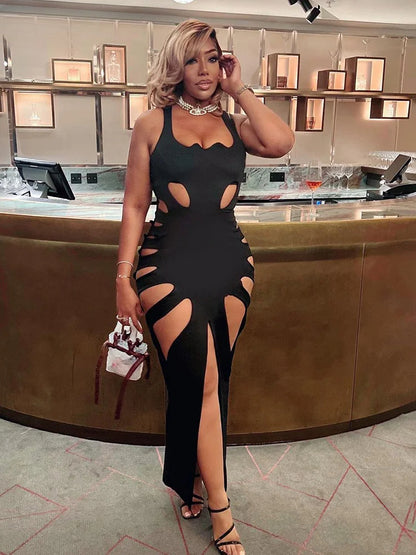 Woman in a black dress with cut-out design standing in a modern interior setting.